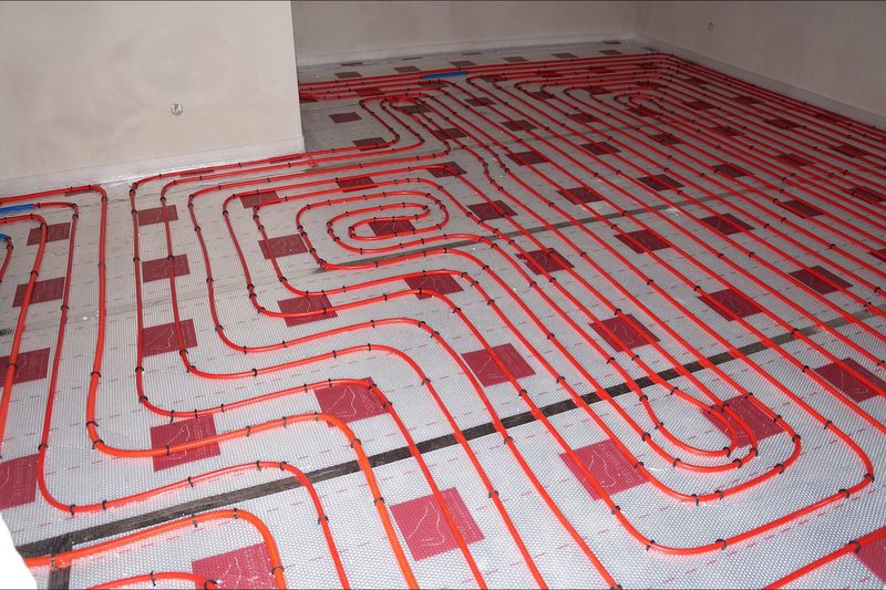 Frisch verlegte Fußbodenheizung mit roten Heizrohren in einem Neubau
